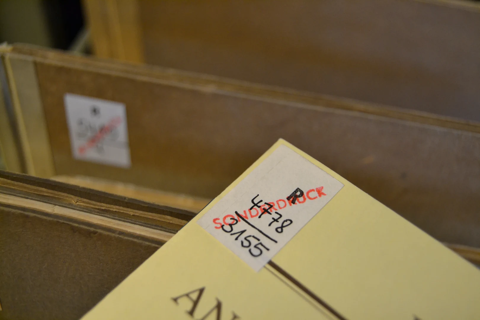 Eine Wissenschaftlerin und ein Wissenschaftler arbeiten hinter einer Glasfassade und mischen Chemikalien mit Großgeräten.