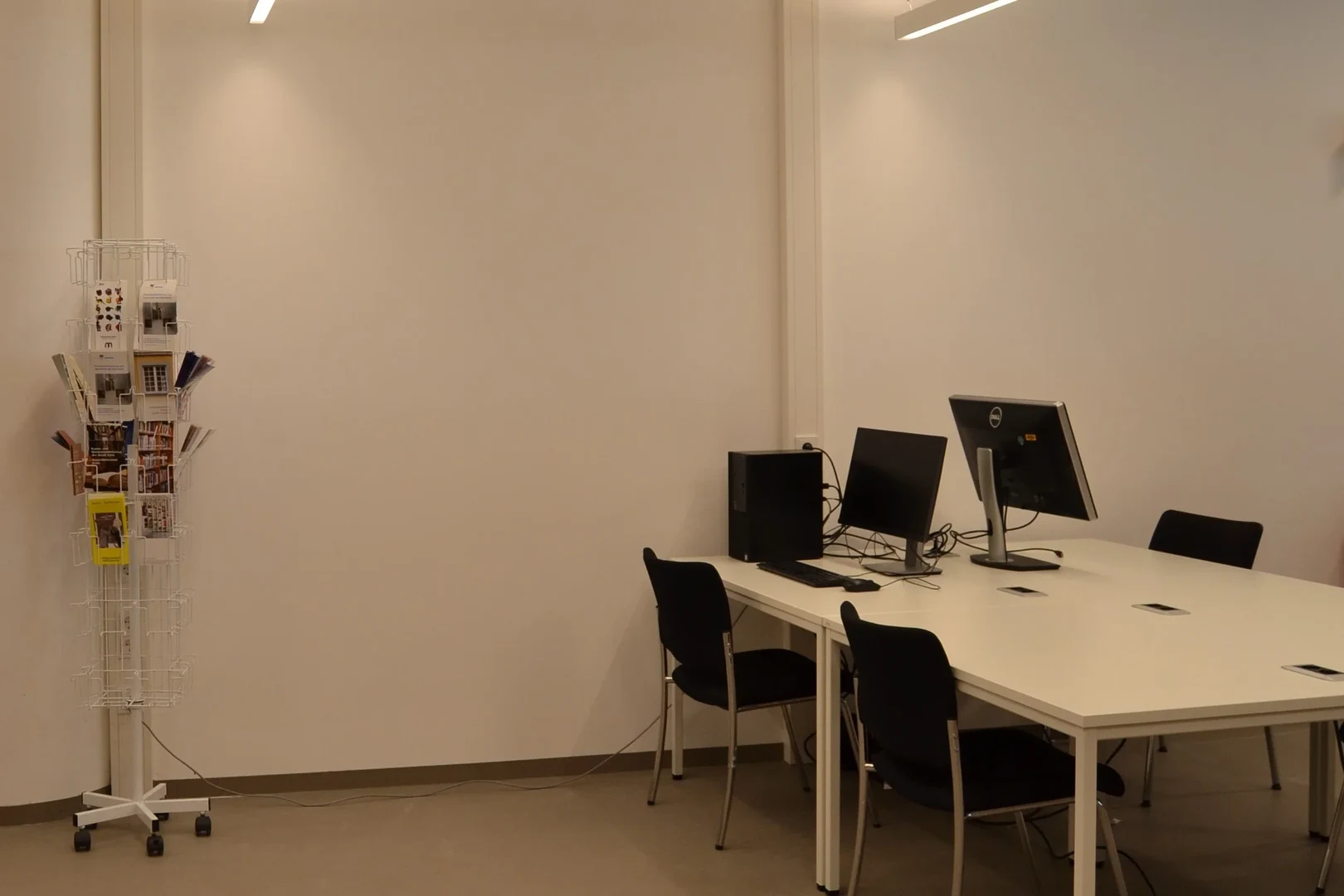 Eine Wissenschaftlerin und ein Wissenschaftler arbeiten hinter einer Glasfassade und mischen Chemikalien mit Großgeräten.