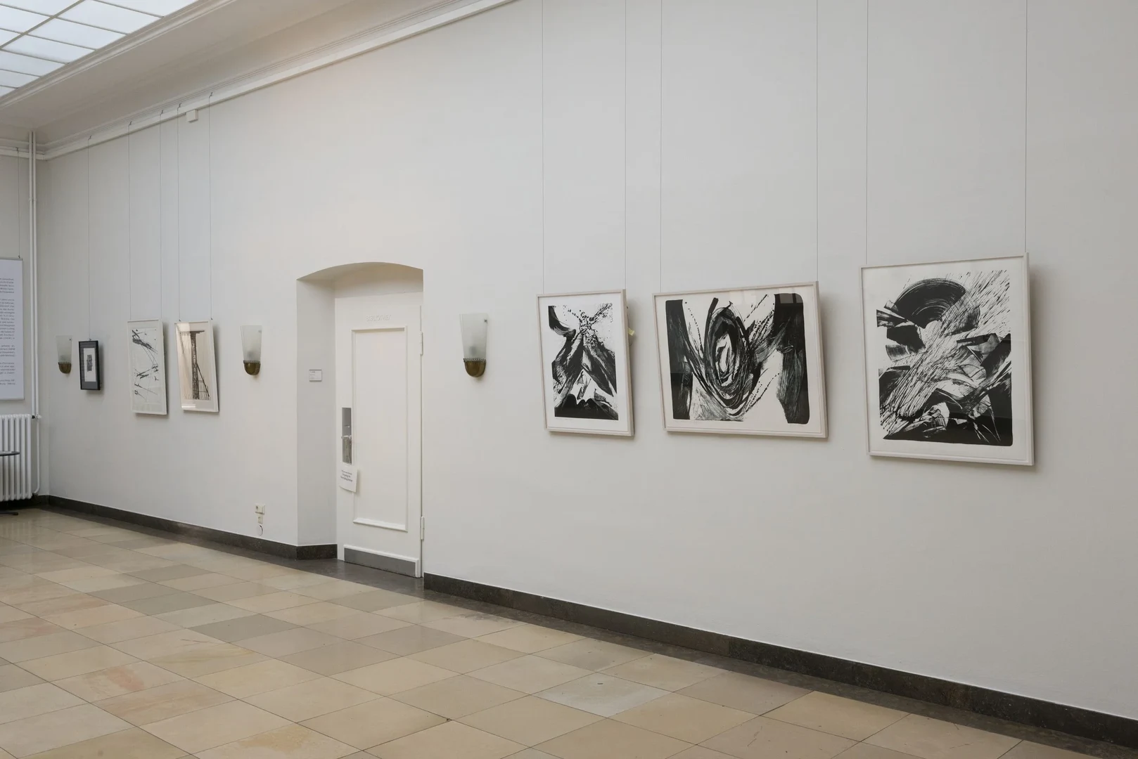 Eine Wissenschaftlerin und ein Wissenschaftler arbeiten hinter einer Glasfassade und mischen Chemikalien mit Großgeräten.