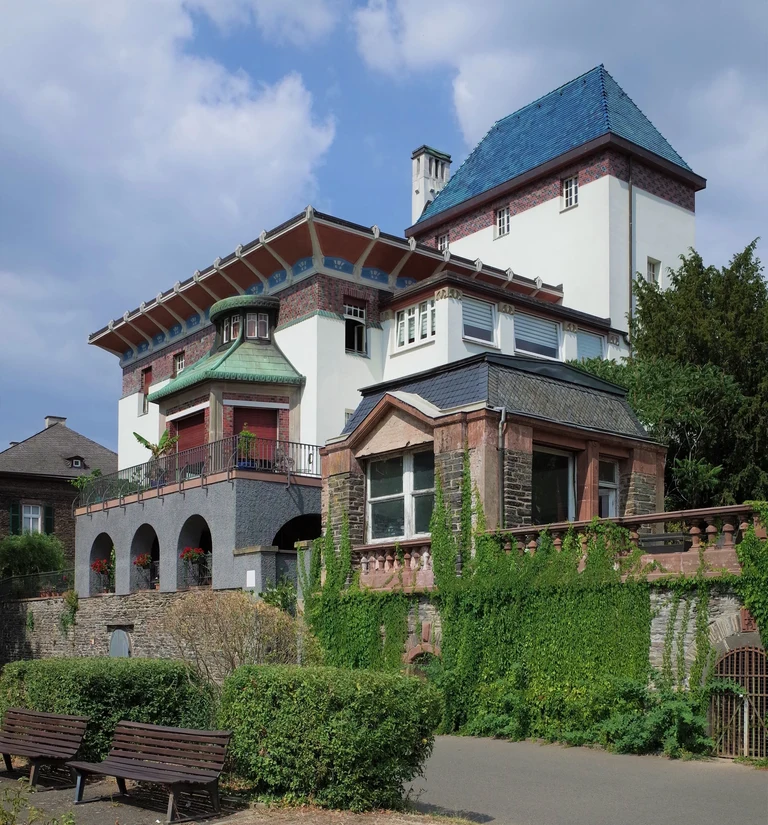 Eine Wissenschaftlerin und ein Wissenschaftler arbeiten hinter einer Glasfassade und mischen Chemikalien mit Großgeräten.