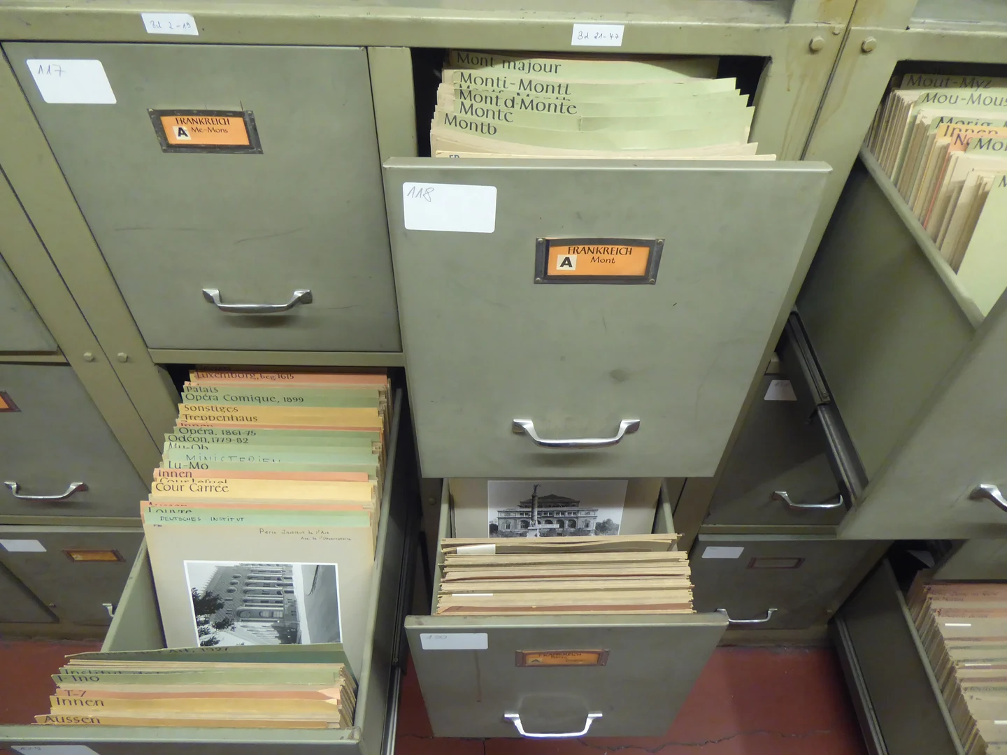 Eine Wissenschaftlerin und ein Wissenschaftler arbeiten hinter einer Glasfassade und mischen Chemikalien mit Großgeräten.