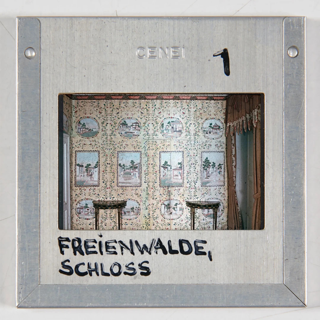 Eine Wissenschaftlerin und ein Wissenschaftler arbeiten hinter einer Glasfassade und mischen Chemikalien mit Großgeräten.