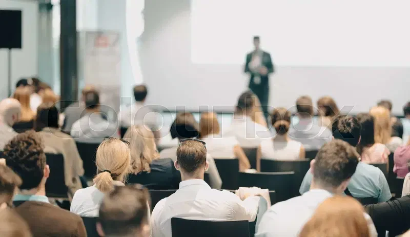 Eine Wissenschaftlerin und ein Wissenschaftler arbeiten hinter einer Glasfassade und mischen Chemikalien mit Großgeräten.