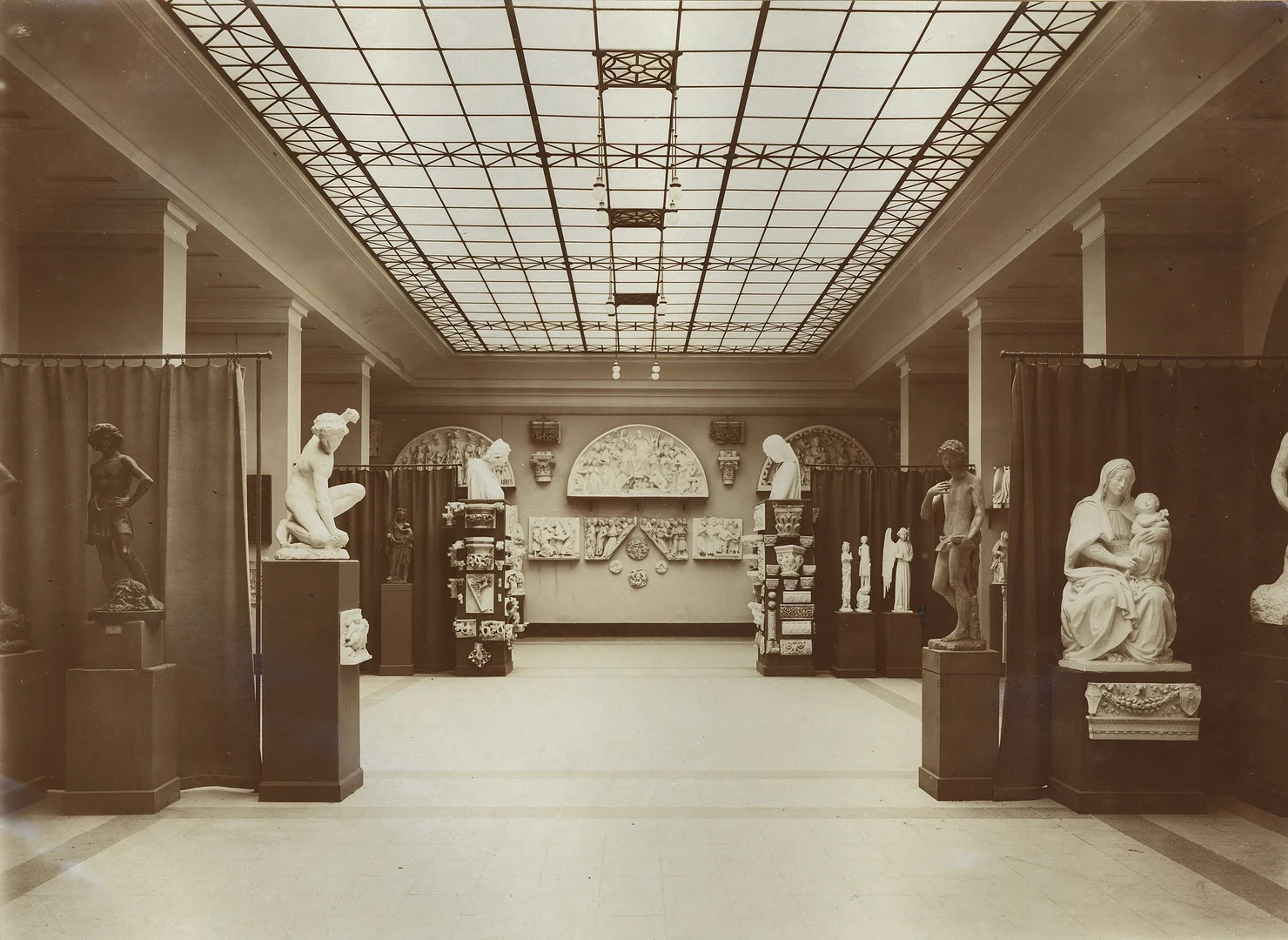 Eine Wissenschaftlerin und ein Wissenschaftler arbeiten hinter einer Glasfassade und mischen Chemikalien mit Großgeräten.