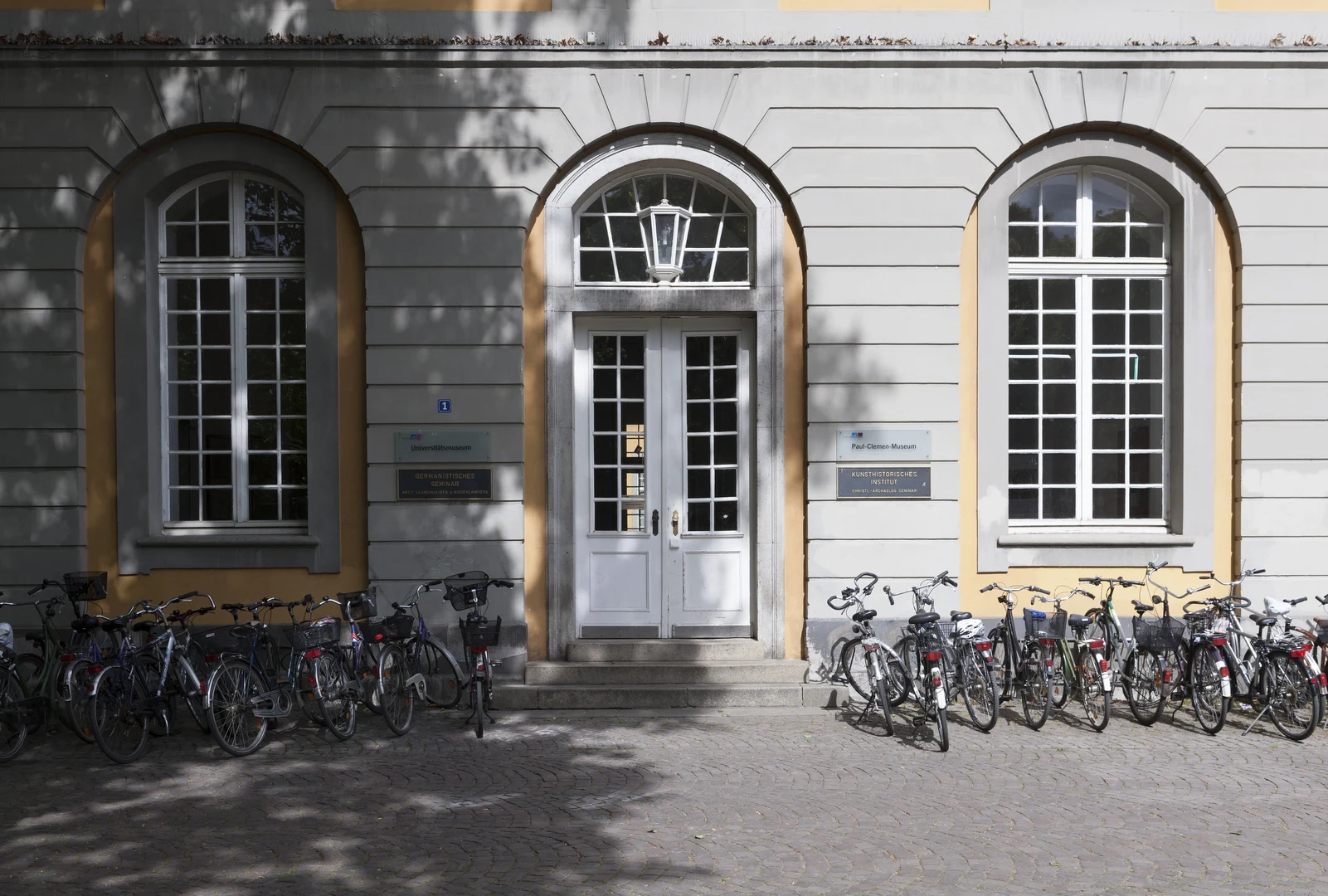 Eine Wissenschaftlerin und ein Wissenschaftler arbeiten hinter einer Glasfassade und mischen Chemikalien mit Großgeräten.