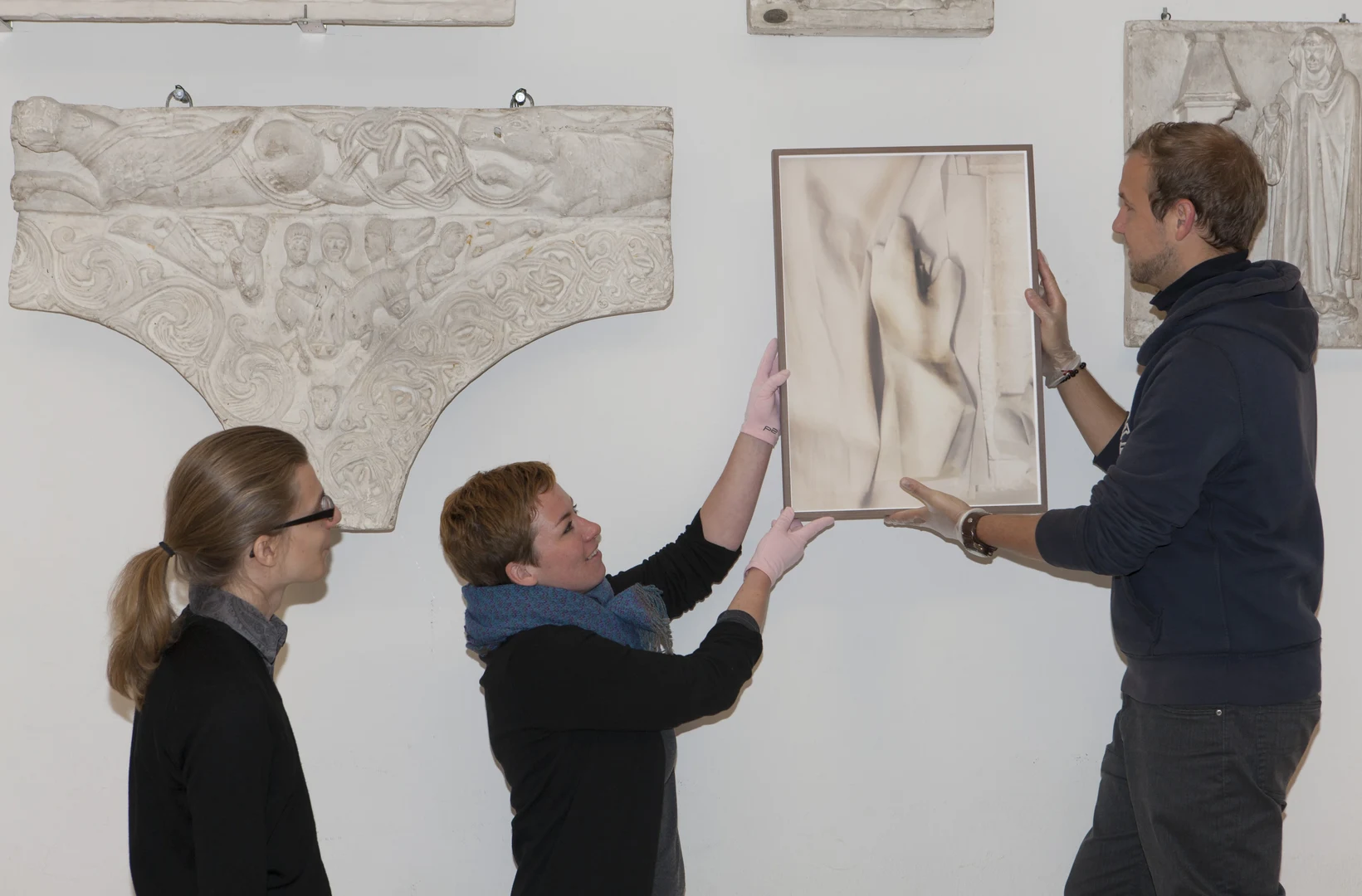 Eine Wissenschaftlerin und ein Wissenschaftler arbeiten hinter einer Glasfassade und mischen Chemikalien mit Großgeräten.