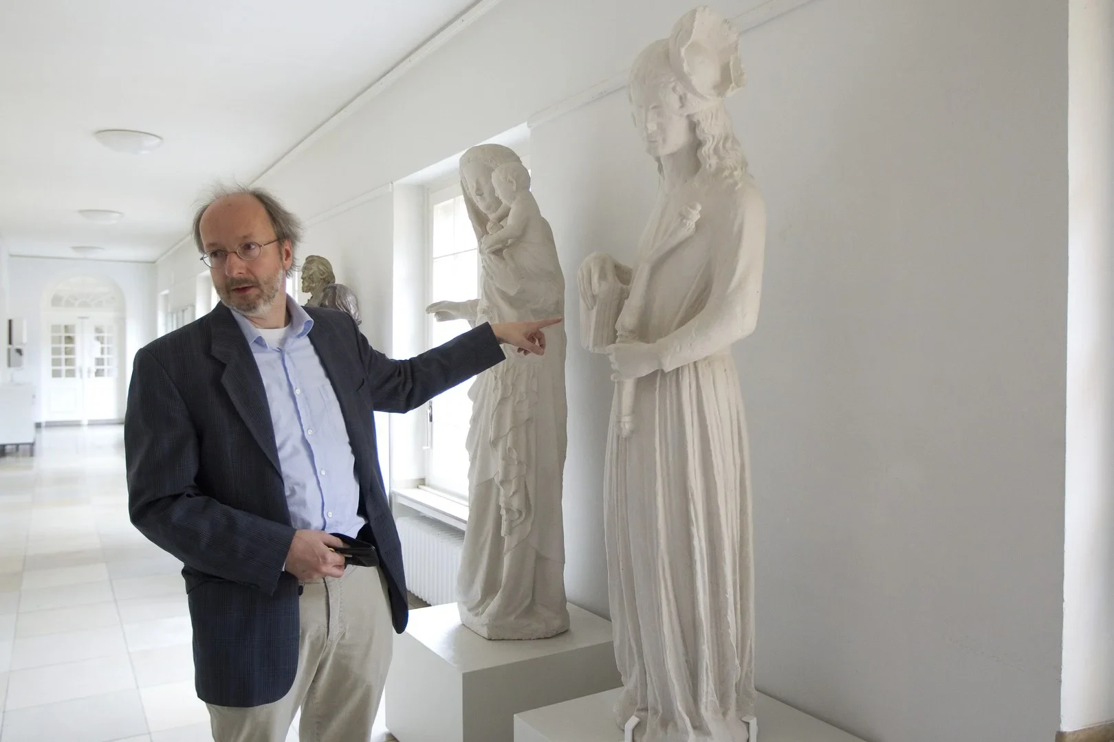 Eine Wissenschaftlerin und ein Wissenschaftler arbeiten hinter einer Glasfassade und mischen Chemikalien mit Großgeräten.