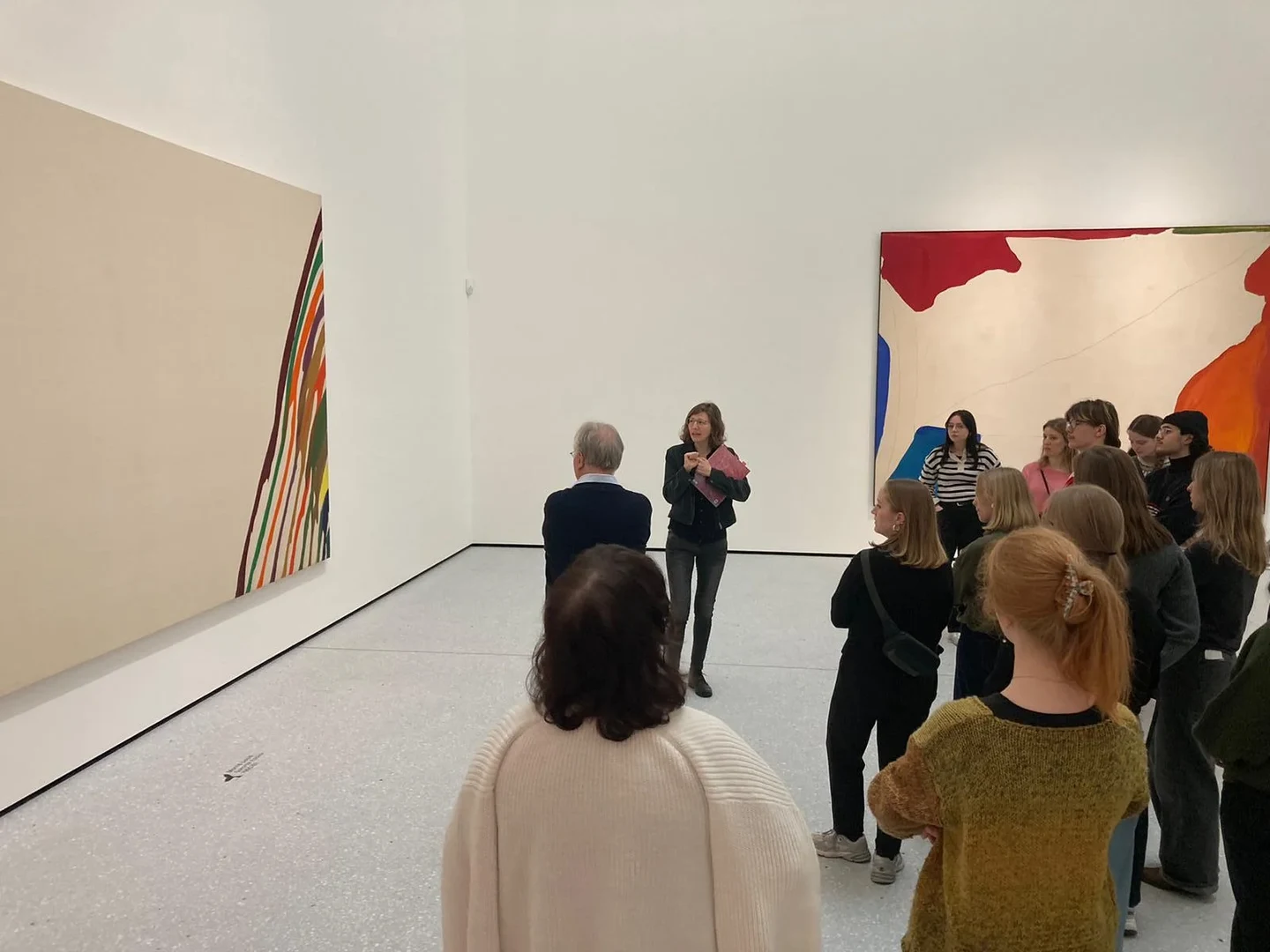 Eine Wissenschaftlerin und ein Wissenschaftler arbeiten hinter einer Glasfassade und mischen Chemikalien mit Großgeräten.