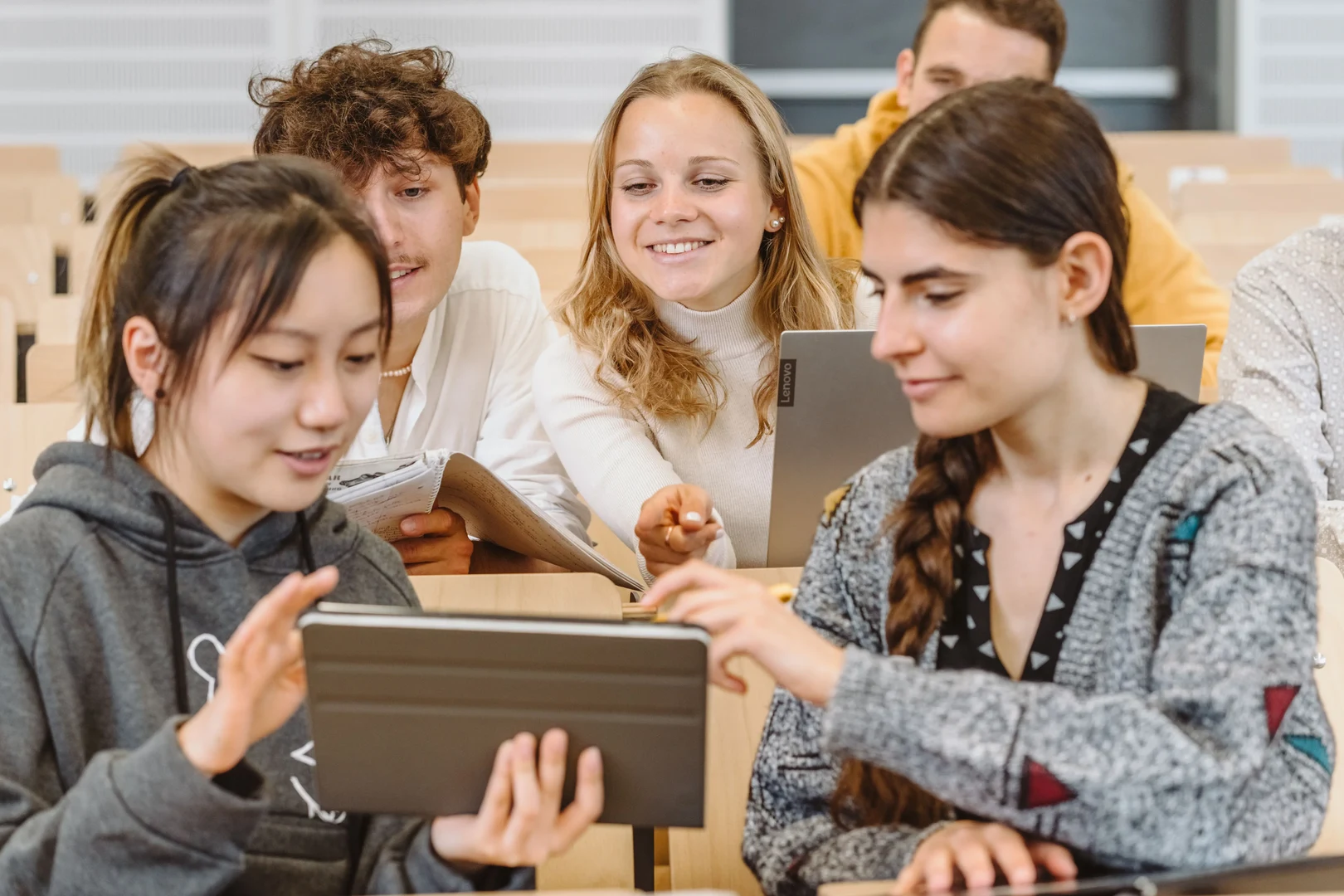 Eine Wissenschaftlerin und ein Wissenschaftler arbeiten hinter einer Glasfassade und mischen Chemikalien mit Großgeräten.